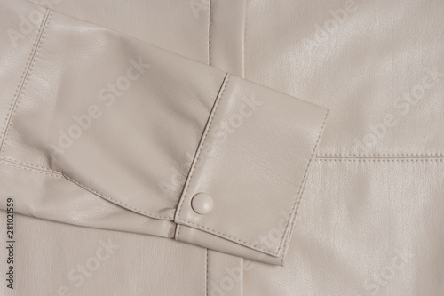 Leather beige sleeve on a stitched material. A sample of good quality sewing. Hand made clothing product. Cuff closeup.