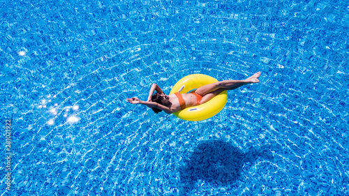 Vacation concept. Top view of slim young woman in bikini on the yellow air inflatable ring in the big swimming pool. © F8  \ Suport Ukraine