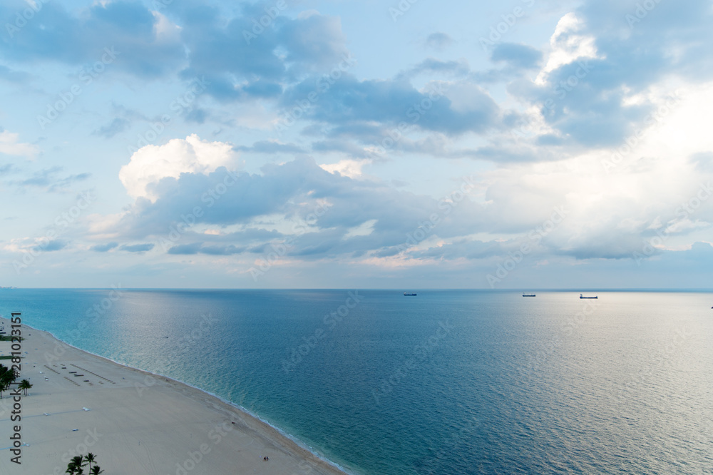 Cloudy day at seaside. White clouds above smooth ocean water