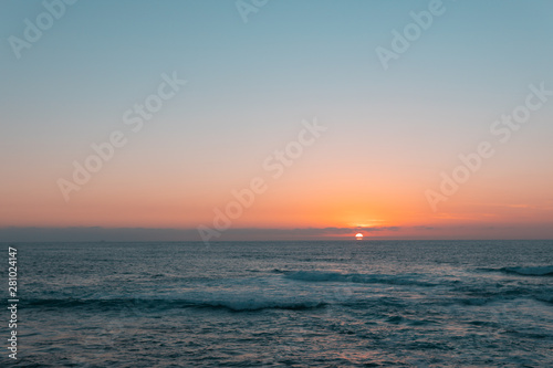Sunset above sea or ocean. Wavy surface of water. Horizon line. Teal and orange colors concept