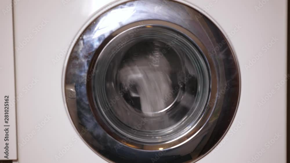 Laundry in washing machine. Working washing machine with clothes, spinning metal drum closeup view. Laundry in washing machine. Working washing machine with clothes, spinning metal drum closeup view.