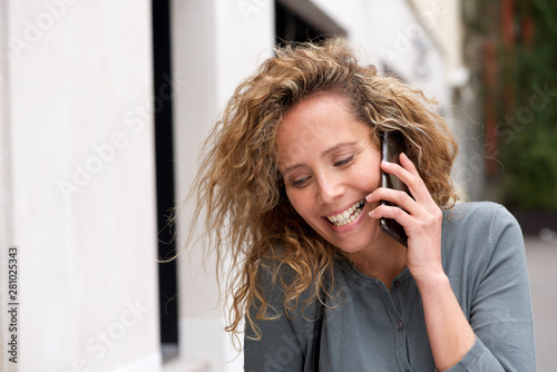 Close up attractive middle age woman smiling while talking with mobile phone