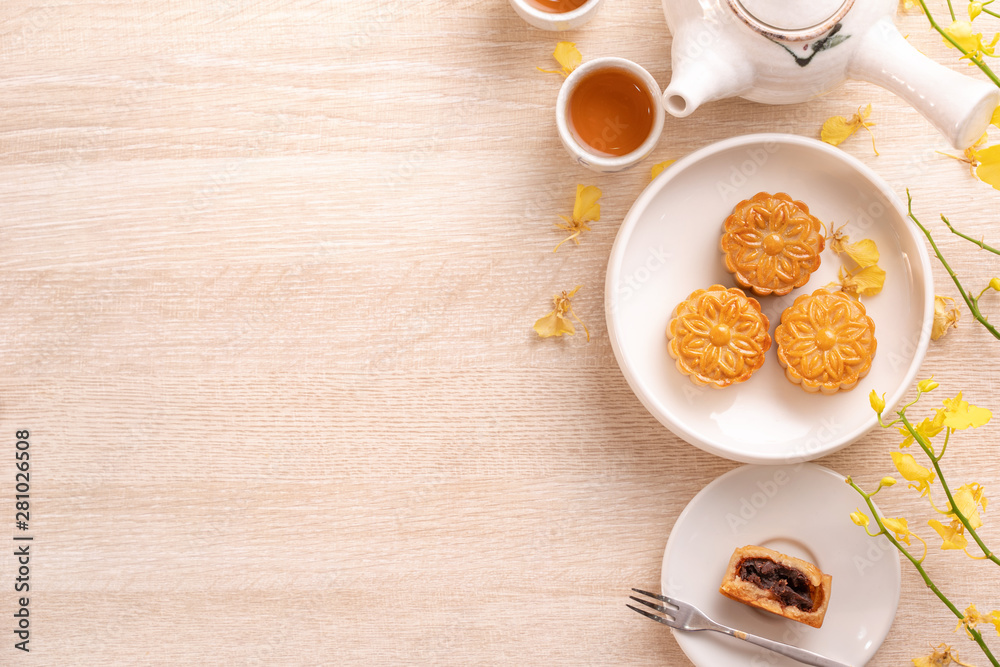 Delicious moon cake for Mid-Autumn festival with beautiful pattern, decorated with yellow flowers and tea. Concept of festive afternoon pastry design Delicious moon cake for Mid-Autumn festival with beautiful pattern, decorated with yellow flowers and tea. Concept of festive afternoon pastry design