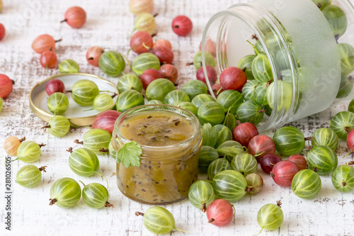 A small glass jar with homemade jam and the fresh gooseberry berries on an old table. Selective focus.