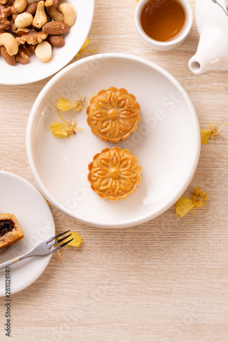 Delicious moon cake for Mid-Autumn festival with beautiful pattern, decorated with yellow flowers and tea. Concept of festive afternoon pastry design