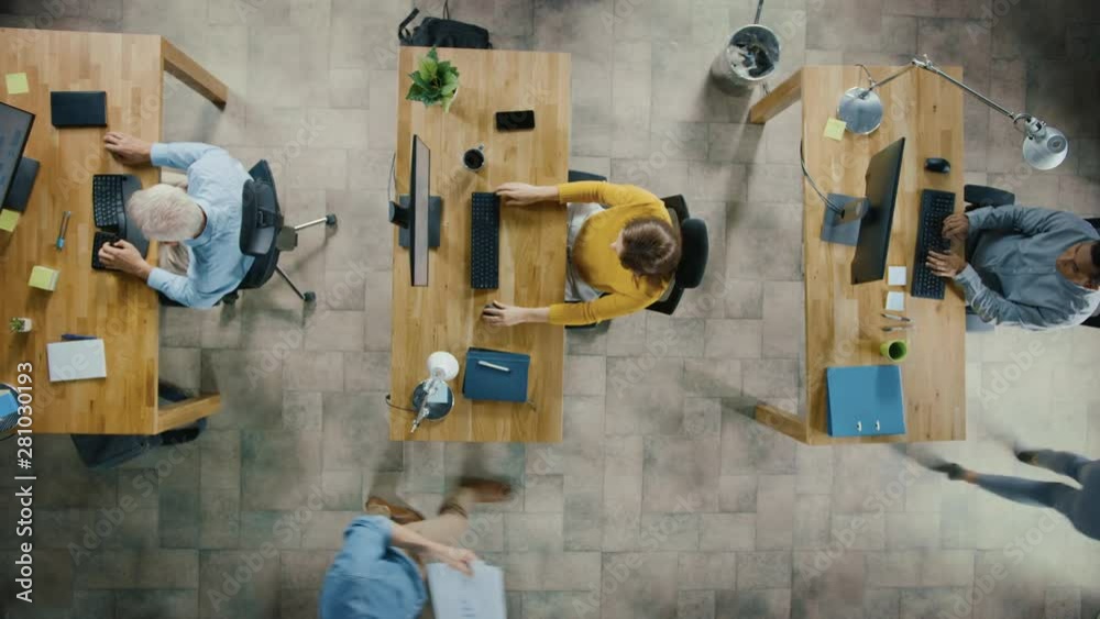 Top View Camera Shot in the Office: Diverse Group of Business Startup Employees Sitting at their Desks Working on Desktop Computers. Stylish and Modern Office Loft with Professionals Doing their Job