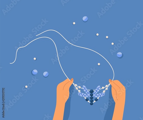 Hands making necklace with seed beads