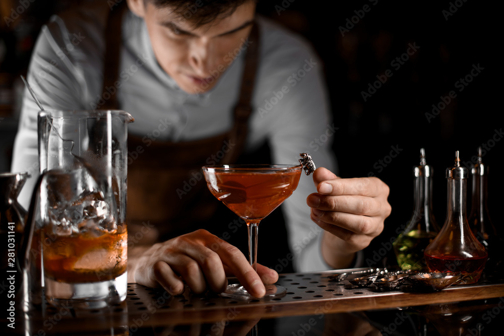 Bartender decorating an alcohol cocktail on bar counter