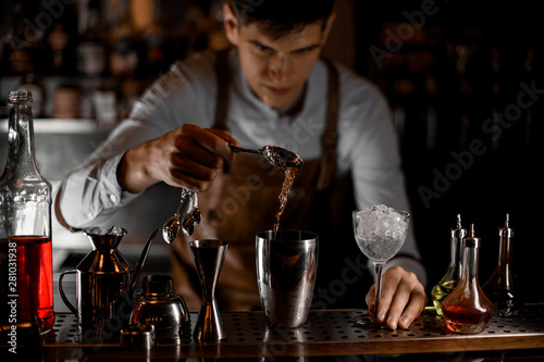 Bartender pours alcohol with spoon and shaker