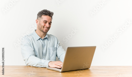 Young handsome man working with his laptop smiling confident with crossed arms.