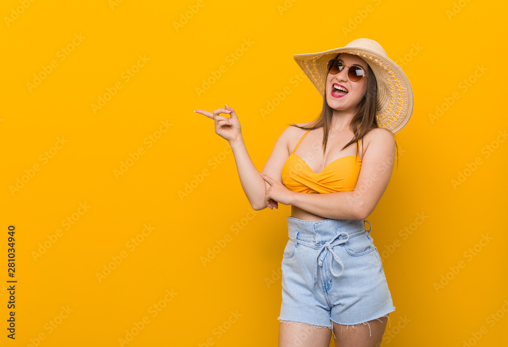 Young caucasian woman wearing a straw hat, summer look smiling cheerfully pointing with forefinger away. Young caucasian woman wearing a straw hat, summer look smiling cheerfully pointing with forefinger away.
