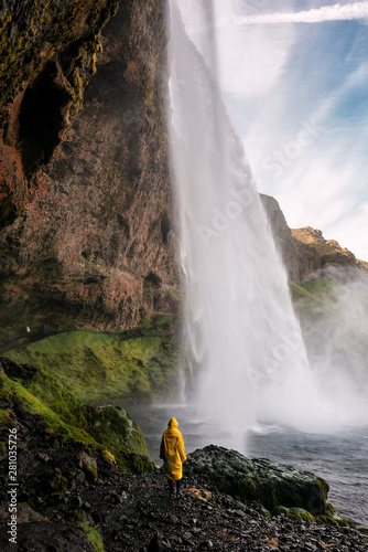 Girl in raincoat and waterfall. Iceland