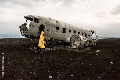 girl in raincoat near remains of the broken plane