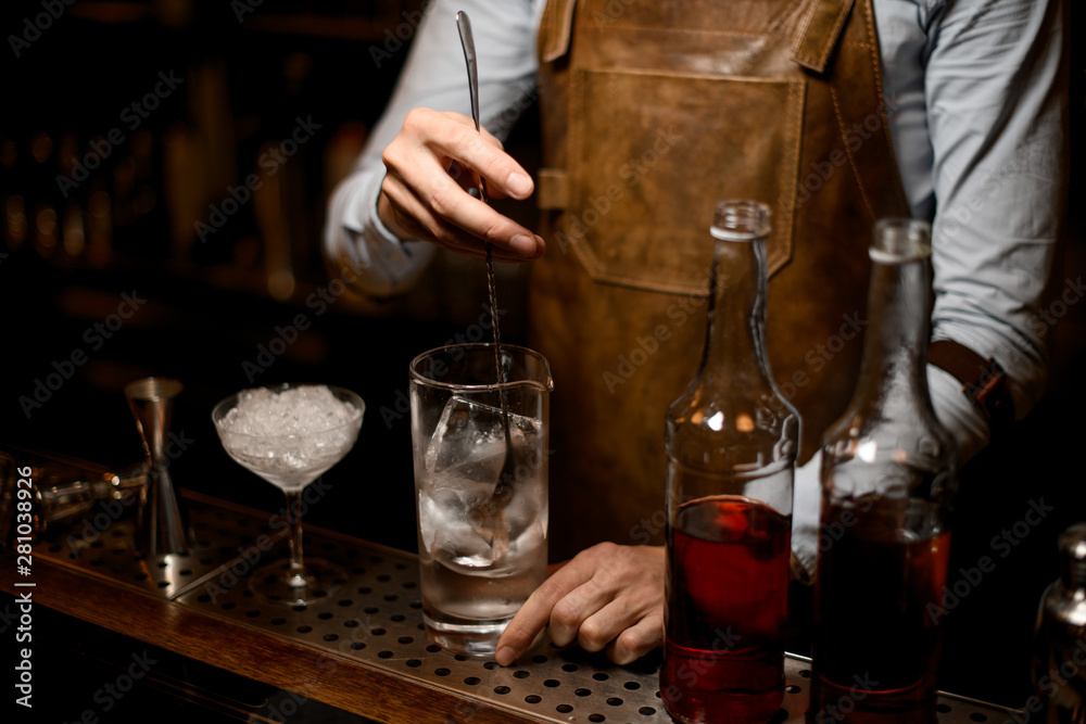 Bartender stirring alcohol cocktail with special spoon