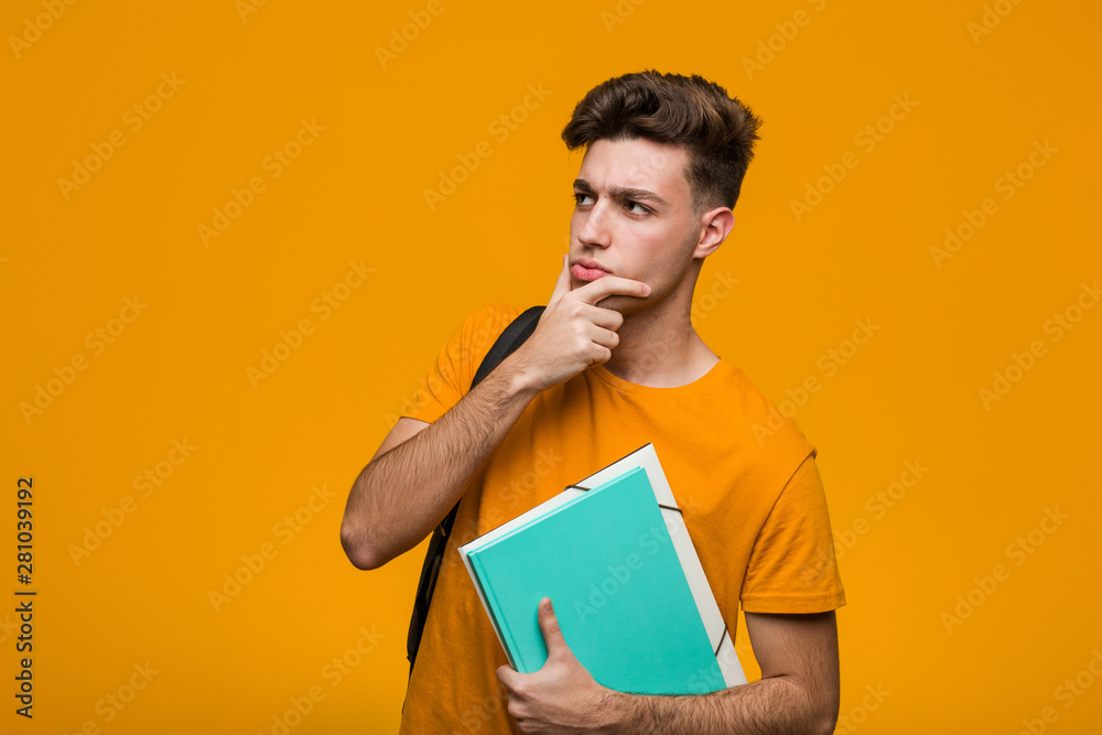 Young student man holding books standing with outstretched hand showing stop sign, preventing you. Young student man holding books standing with outstretched hand showing stop sign, preventing you.