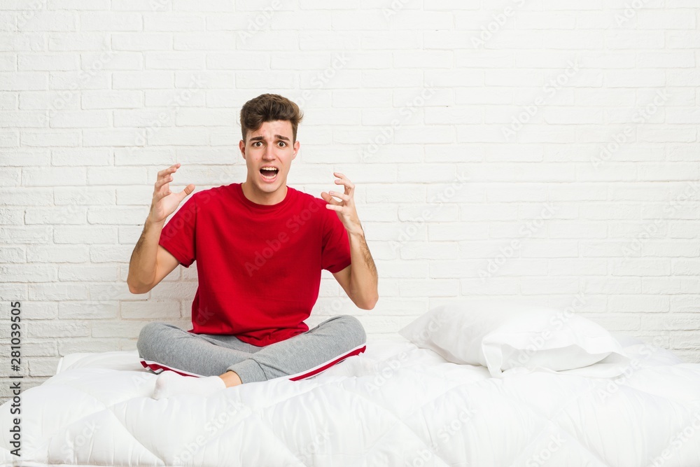 Young teenager student man on the bed screaming with rage. Young teenager student man on the bed screaming with rage.