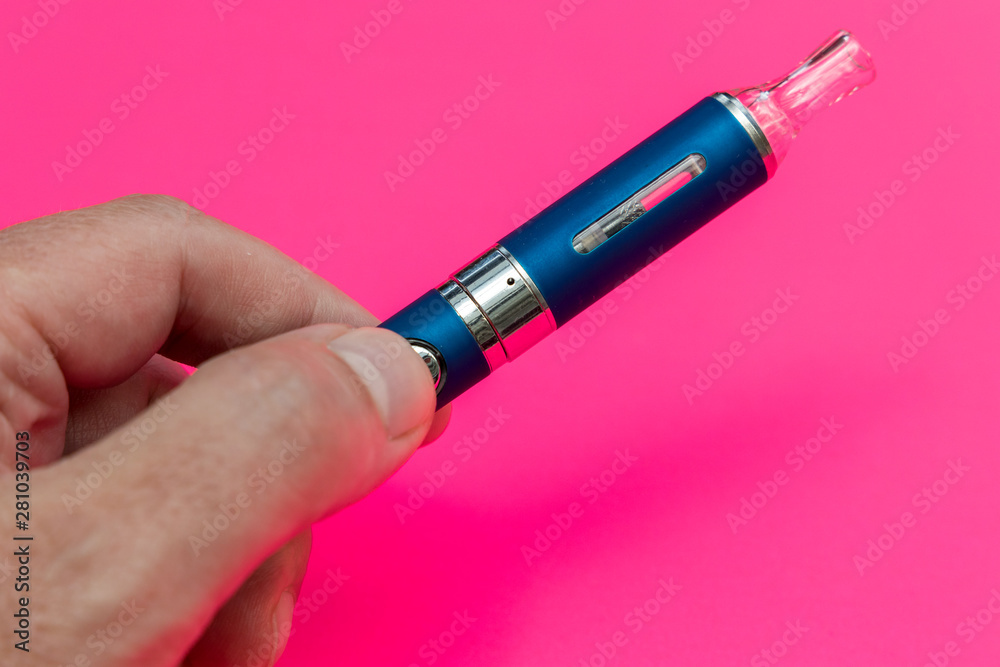 Hand holding vape pen metal electronic cigarette with vaping pink background Hand holding vape pen metal electronic cigarette with vaping pink background