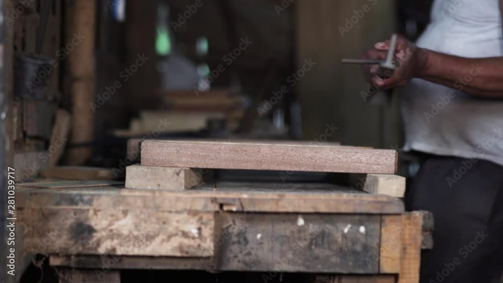 Worksman at a carpentry factory is polishing  wooden construction