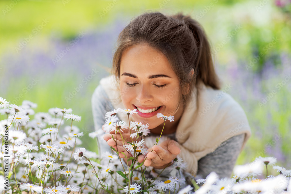 gardening and people concept - close up of happy young woman smelling chamomile flowers at summer garden gardening and people concept - close up of happy young woman smelling chamomile flowers at summer garden