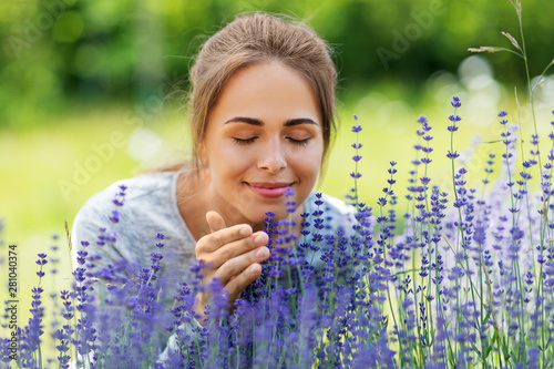 gardening and people concept - happy young woman smelling lavender flowers at summer garden