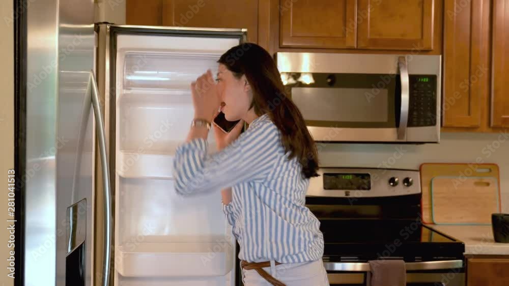 elegant office lady in casual wear walking busy in wooden old kitchen at home. young asian female talking on mobile phone opening fridge. woman on smartphone leaning on table relax holding cup coffee elegant office lady in casual wear walking busy in wooden old kitchen at home. young asian female talking on mobile phone opening fridge. woman on smartphone leaning on table relax holding cup coffee