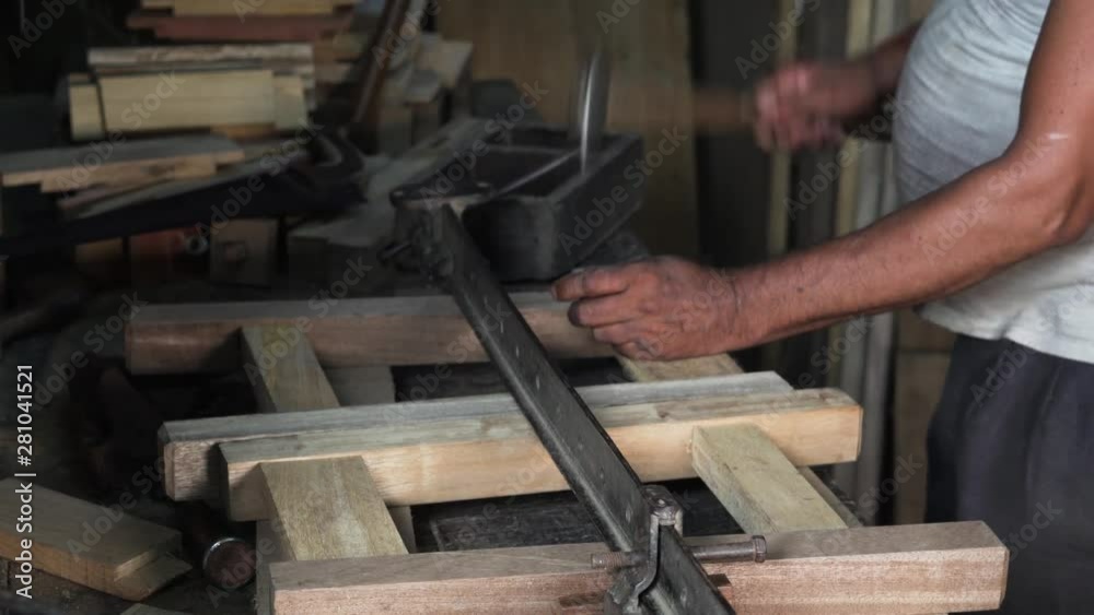 A carpenter working with nails and a hammer to assemble the parts of a wooden construction A carpenter working with nails and a hammer to assemble the parts of a wooden construction