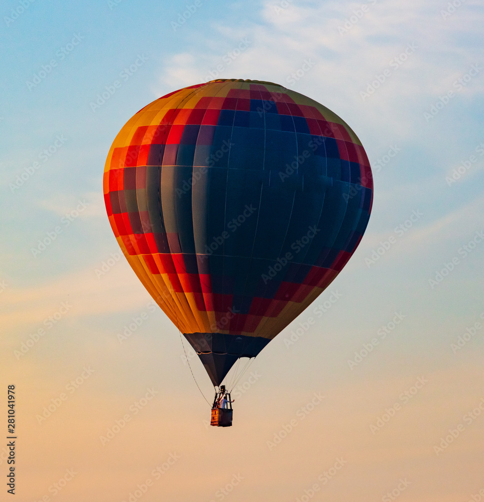 Fototapeta premium Balon lecący na niebie w promieniach zachodzącego słońca