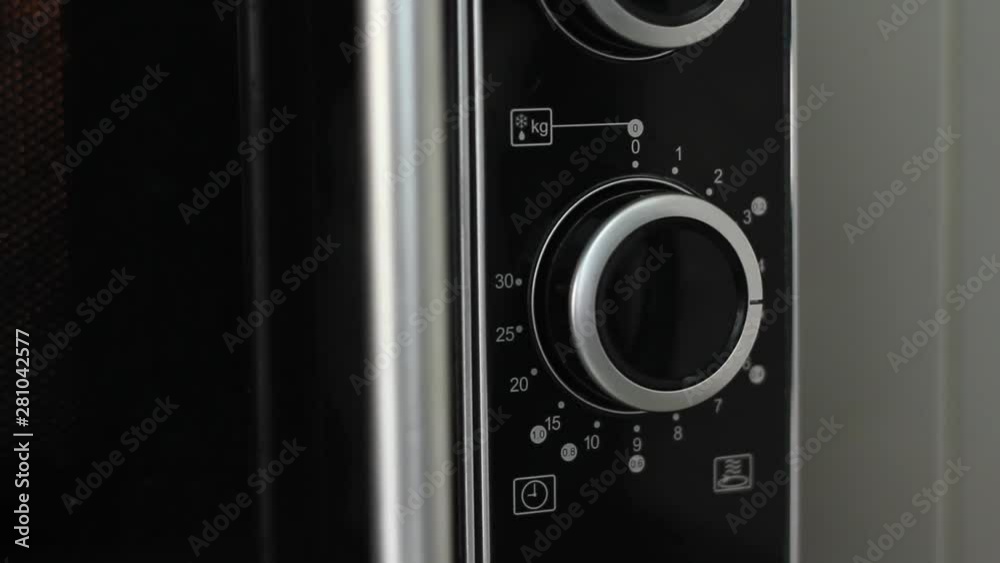 Setting microwave timer to five minutes and turning microwave off - close angled shot Setting microwave timer to five minutes and turning microwave off - close angled shot