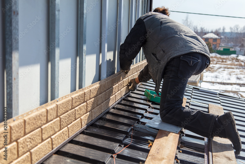 Worker installs plastic panels with bricks