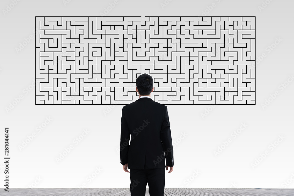 Businessman in doubt looking to a maze and searching the way out Businessman in doubt looking to a maze and searching the way out