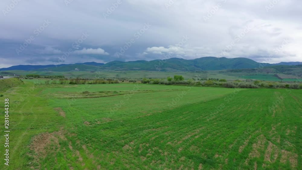 Spring field on the background of mountains. Cloudy sky Aerial view Spring field on the background of mountains. Cloudy sky Aerial view