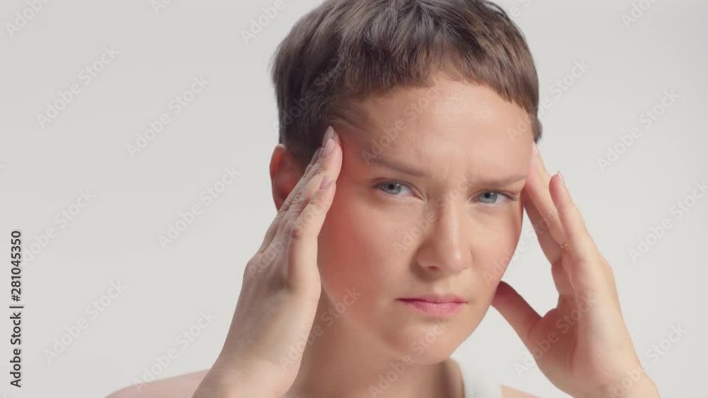 caucasian blue eyed model alone in studio massage her temples head ache concept
