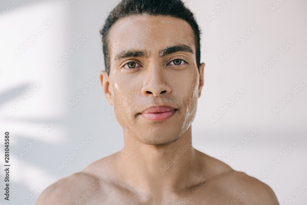 Obraz premium handsome serious young man with wet face looking at camera