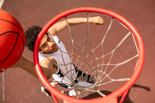 View of basket with net and young player throwing ball below