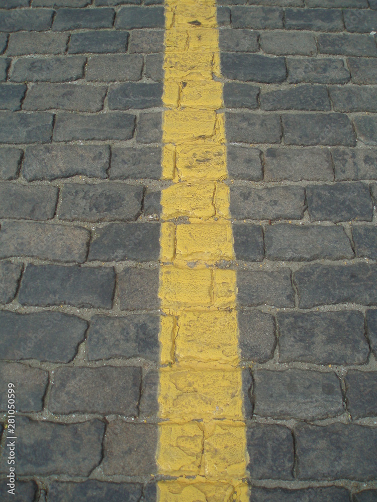 asphalt background texture with shades and spots of yellow line on the cobbles