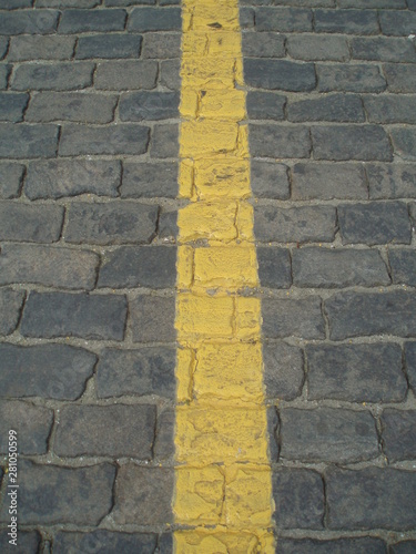 asphalt background texture with shades and spots of yellow line on the cobbles