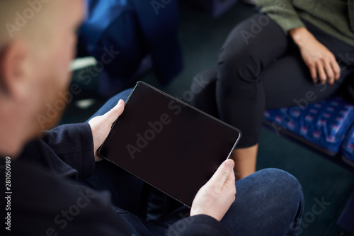 Close Up Of Male Passenger Sitting In Train With Digital Ticket On Tablet Computer