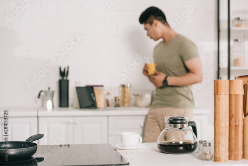 Foto selective focus of young asian man holding glass with orange juice in kitchen