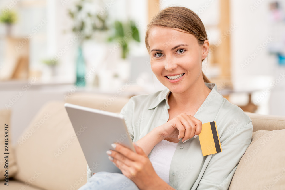 Happy girl using tablet to search for online goods and plastic card for payment Happy girl using tablet to search for online goods and plastic card for payment