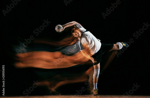 Caucasian young handball player in action and motion in mixed lights over black studio background. Fit male professional sportsman. Concept of sport, movement, energy, dynamic, healthy lifestyle.
