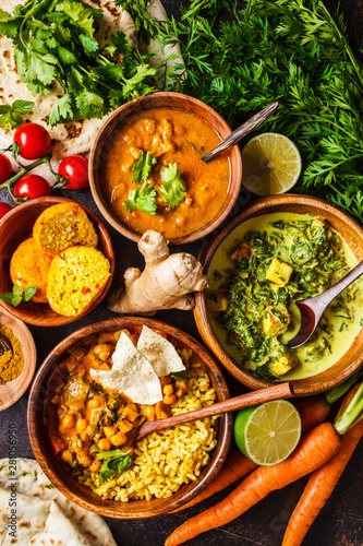 Food traditional Indian cuisine. Dal, palak paneer, curry, rice, chapati, chutney in wooden bowls on dark background.