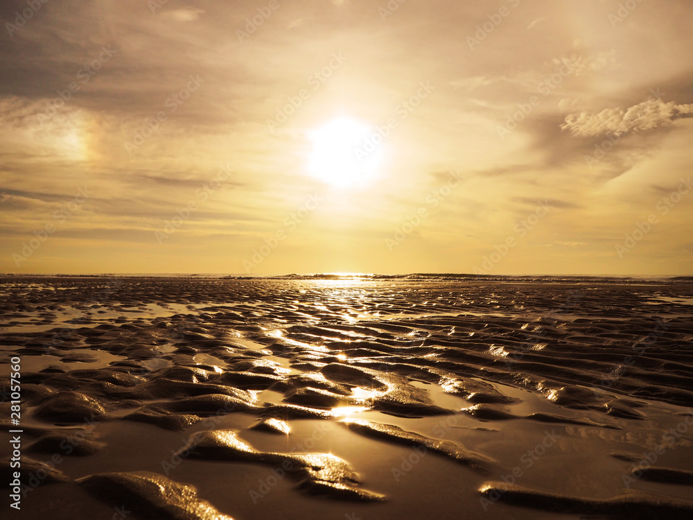 Obraz premium Golden sand ripples surface pattern on sunset beach.