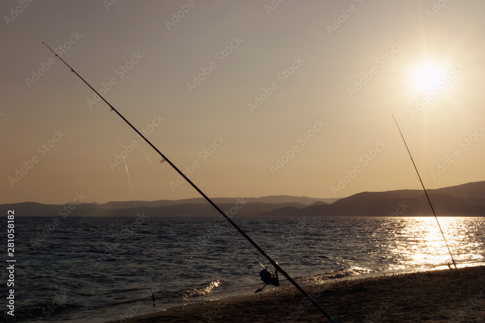 Fishing rods on beach shore at sunset