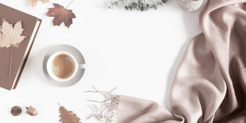 Autumn home cozy composition. Dried autumn leaves, cup of coffee, book, scarf, flowers on white background. Fall background. Flat lay, top view, copy space