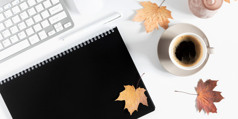 Autumn home cozy composition. Women's home office desk. Dried autumn leaves, cup of coffee, computer, notebook, flowers on white background. Fall background. Flat lay, top view, copy space