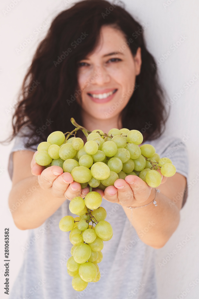 Beautiful woman, holding fresh green grape in handful, isolated on white background. Vertical image Beautiful woman, holding fresh green grape in handful, isolated on white background. Vertical image
