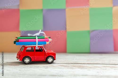 Miniature Red Car Carrying a colorful pencils on wooden table. Back to school concept