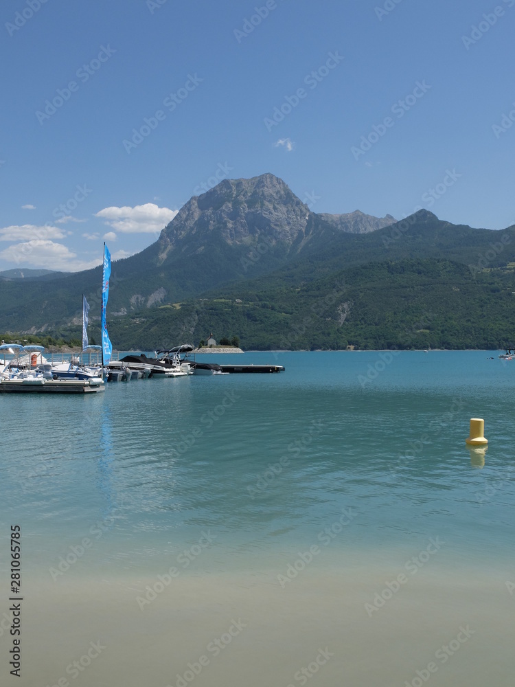 eau bleue du lac de serre Ponçon, bateau et montagne