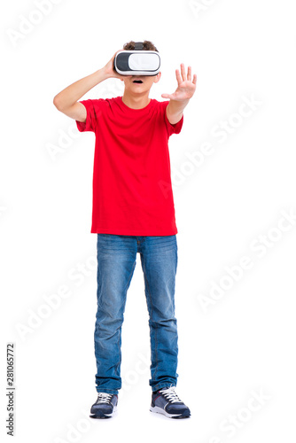 Full length portrait of young caucasian teen boy using virtual reality goggles. Funny teenager looking in VR glasses. Handsome child experiencing 3D gadget technology, isolated on white background. © valiza14