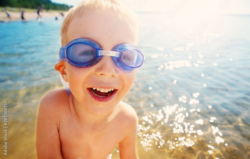 four years old boy playing at the beach with swimming glasses
